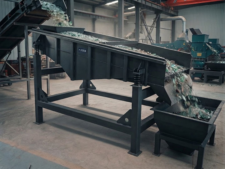 Dahan linear vibrating scalping sieve separating glass cullet in an industrial recycling plant, showing material flow and heavy-duty construction.
