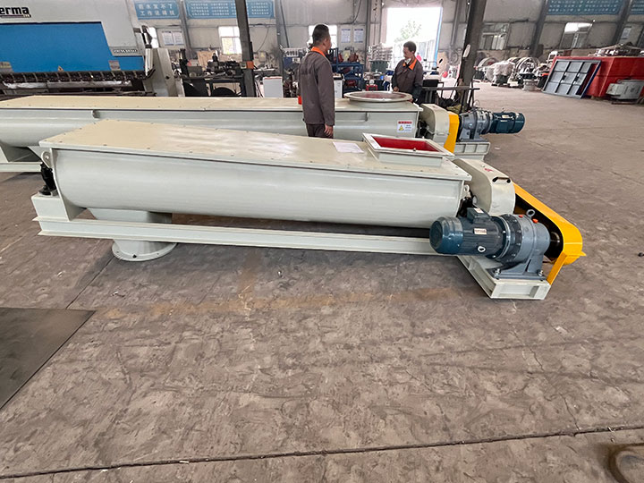 Two heavy-duty industrial screw conveyor systems manufactured by Dahan Feeders on factory floor