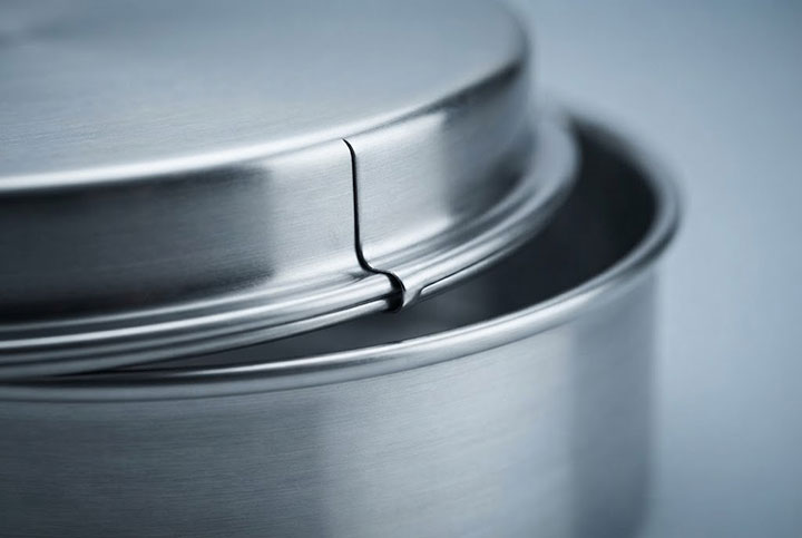 Extreme close-up macro shot of industrial-grade stainless steel test sieve pan and cover, highlighting precise rim rolling and metal forming quality.